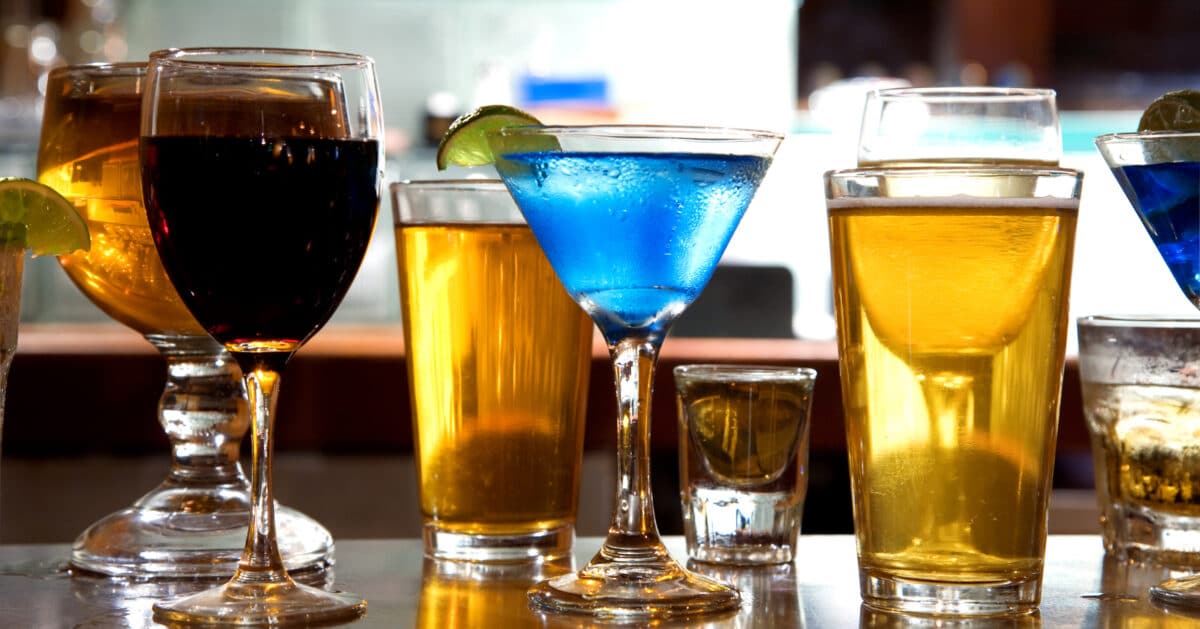 Blue cocktail drink in a martini glass with other drinks in the background