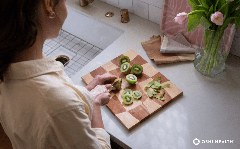 Person cutting up kiwi fruit on a kitchen counter