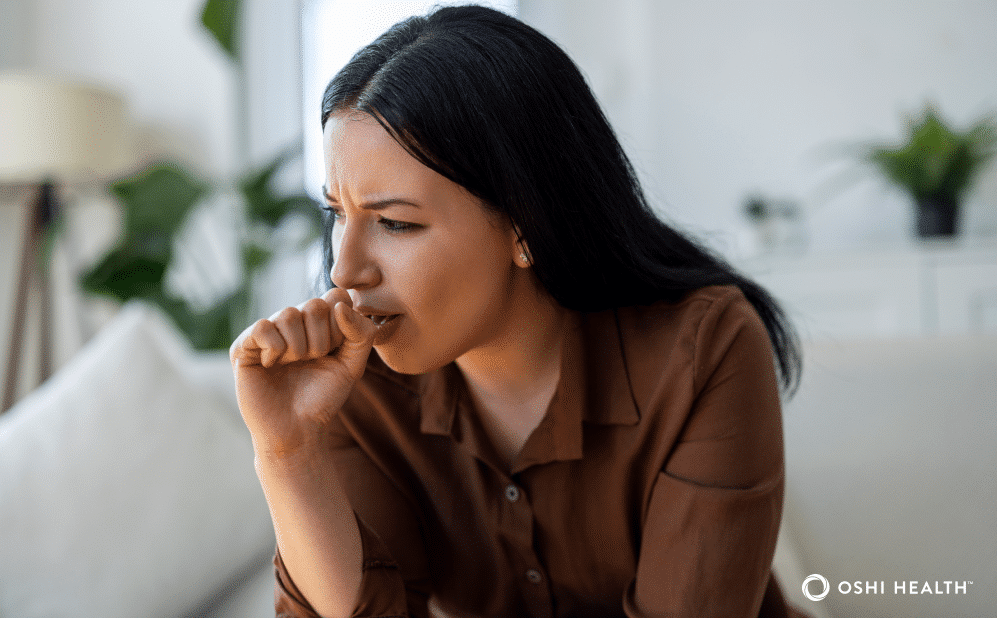 Person covering their mouth while coughing, illustrating a cough that may be related to acid reflux.