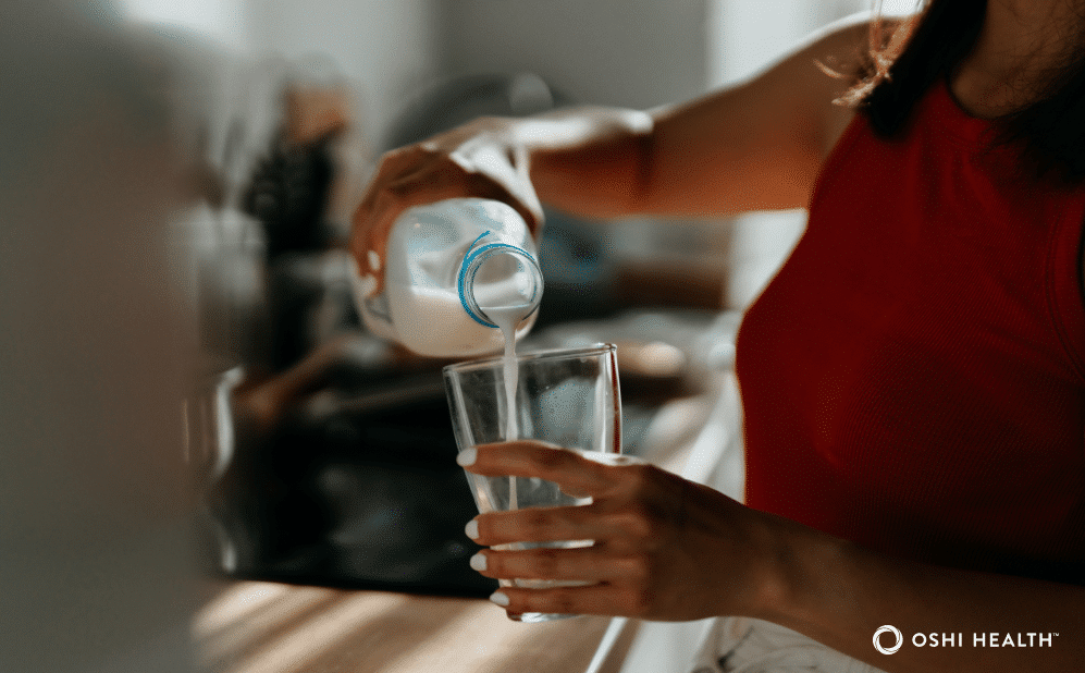Photo of a person pouring milk into a glass in a kitchen.